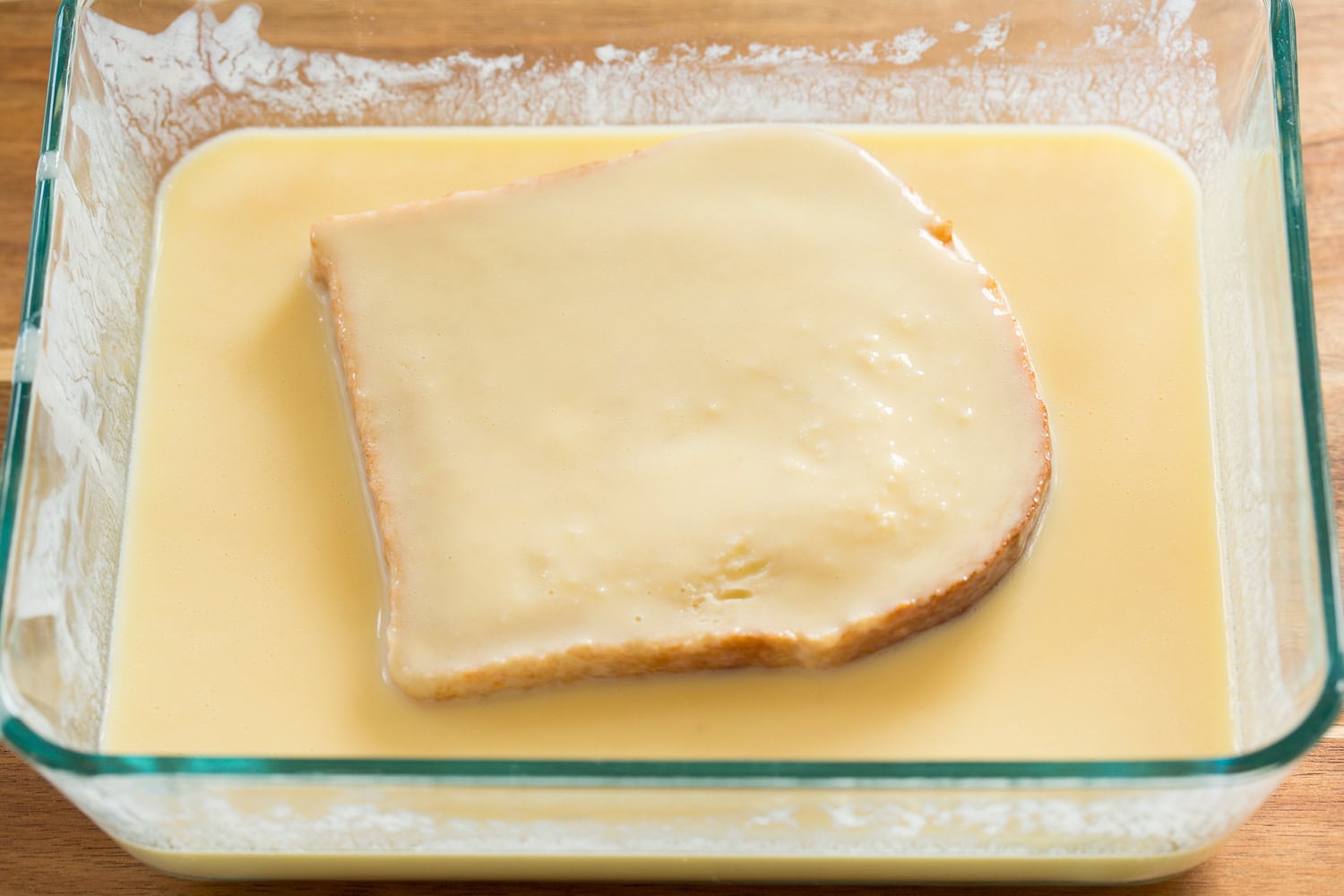 French bread being soaked in buttermilk egg mixture.