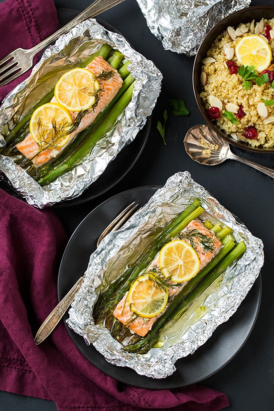 Two plates of Salmon and Asparagus in Foil topped with lemon wedges