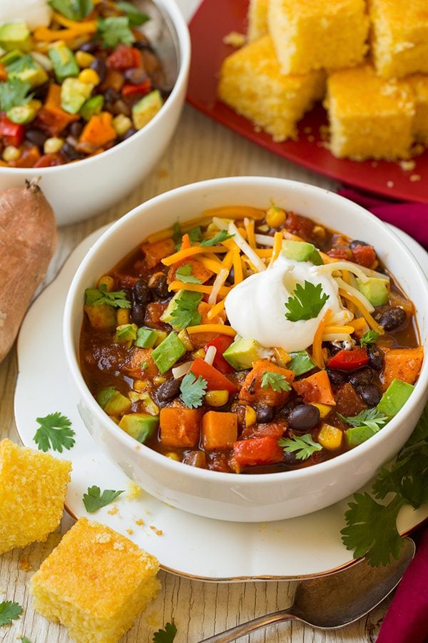 Sweet potato chili in a serving bowl garnished with avocado, cheese, sour cream and cilantro.