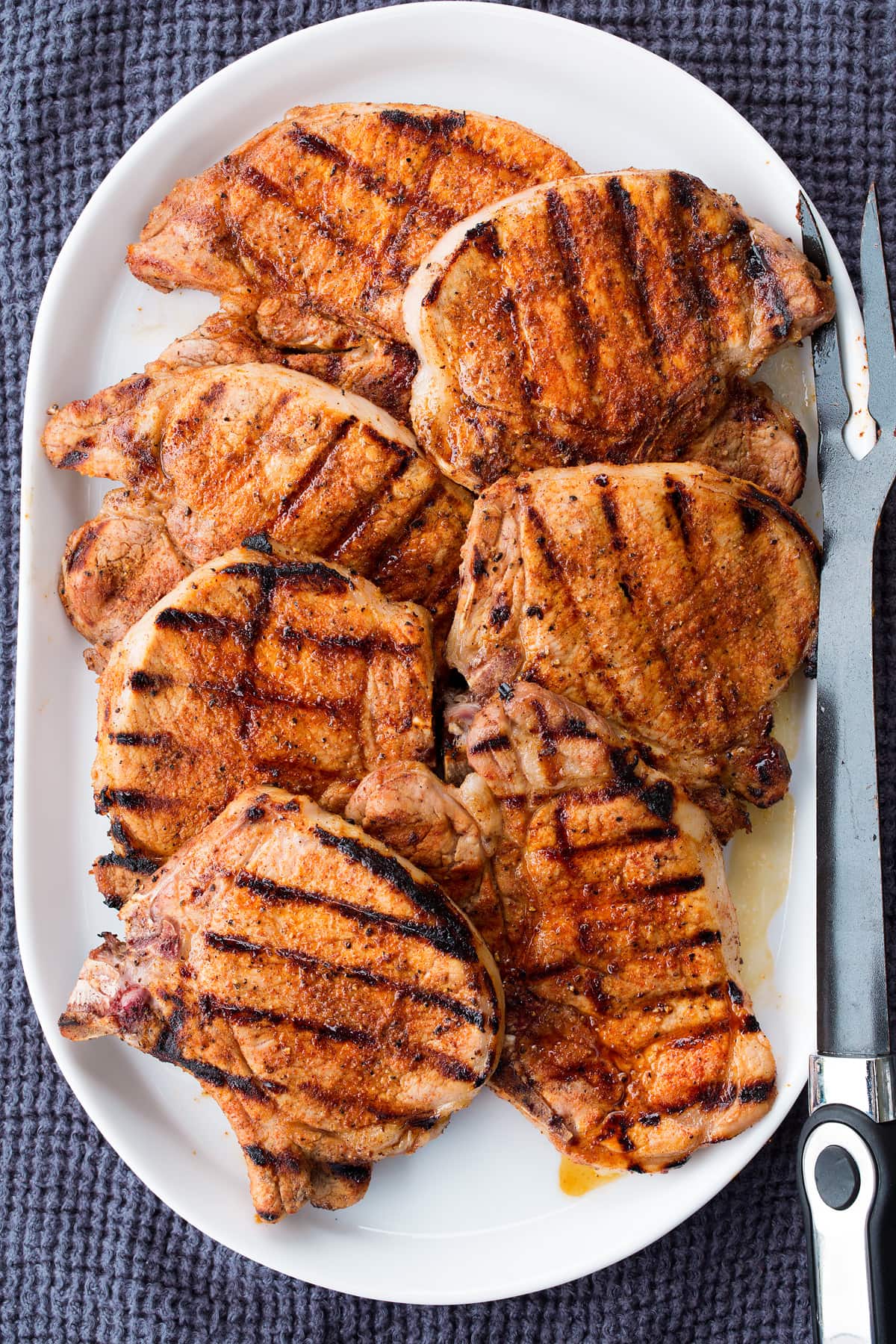 Grilled pork chops on a white oval platter.