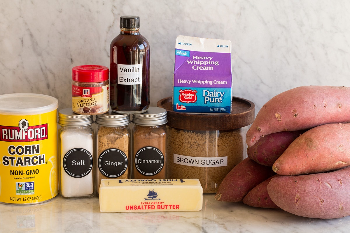 Image of ingredients used to make candied yams. Includes sweet potatoes, brown sugar, cream, butter, cinnamon, nutmeg, ginger, salt, vanilla and cornstarch.