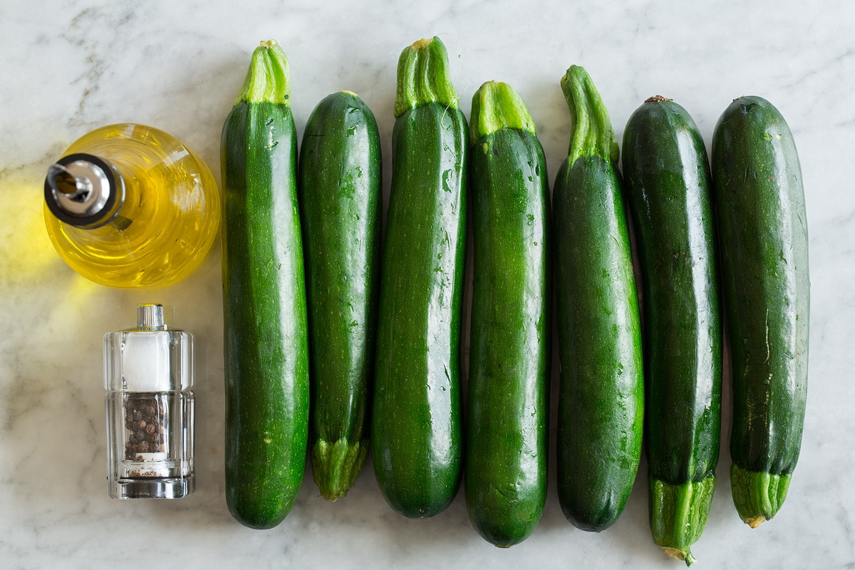 Image of ingredients used to make zucchini noodles. Includes fresh zucchini, olive oil, salt and pepper.