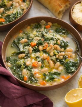 Serving of white bean and kale soup in a brown bowl.