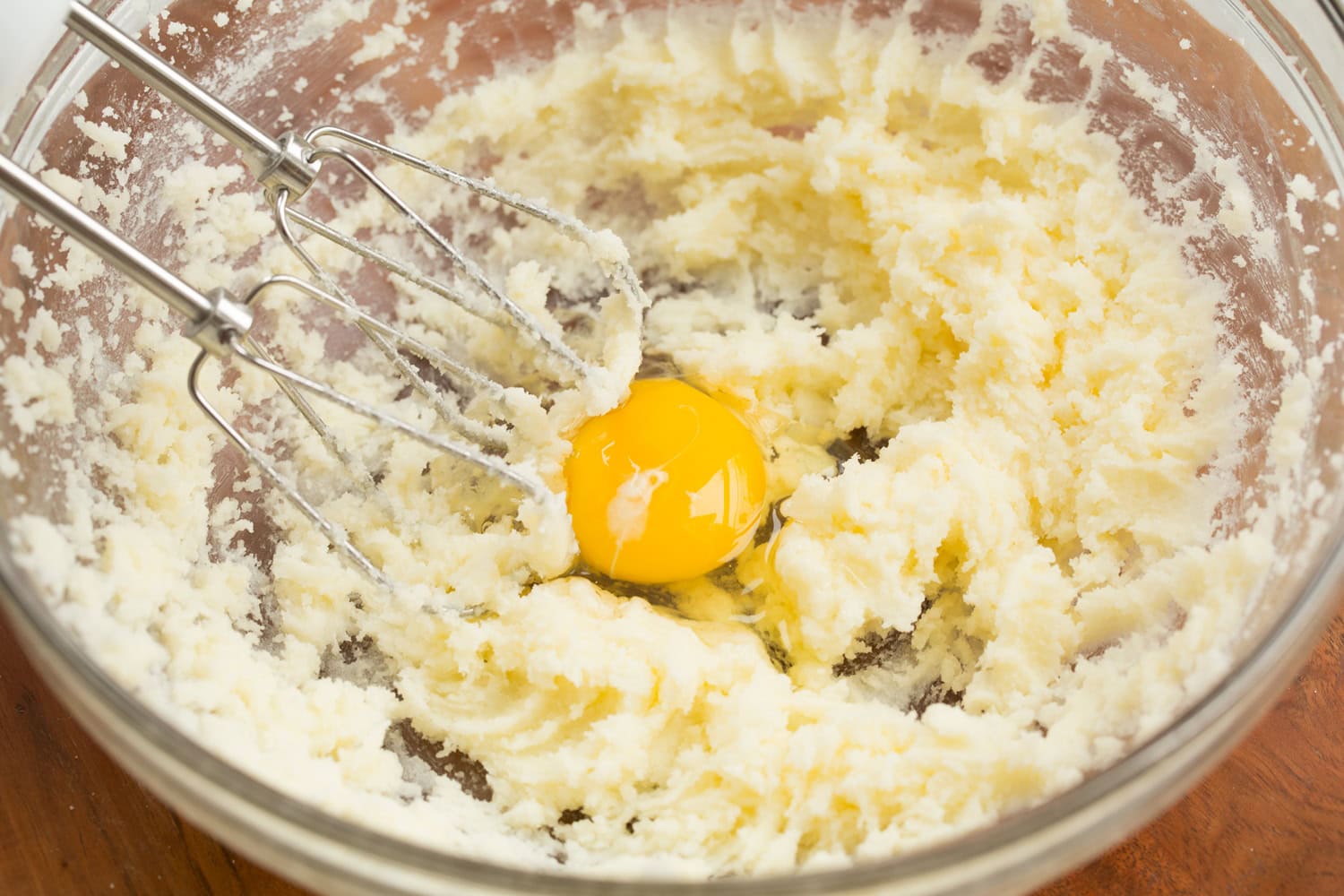 Adding egg to cupcake batter.
