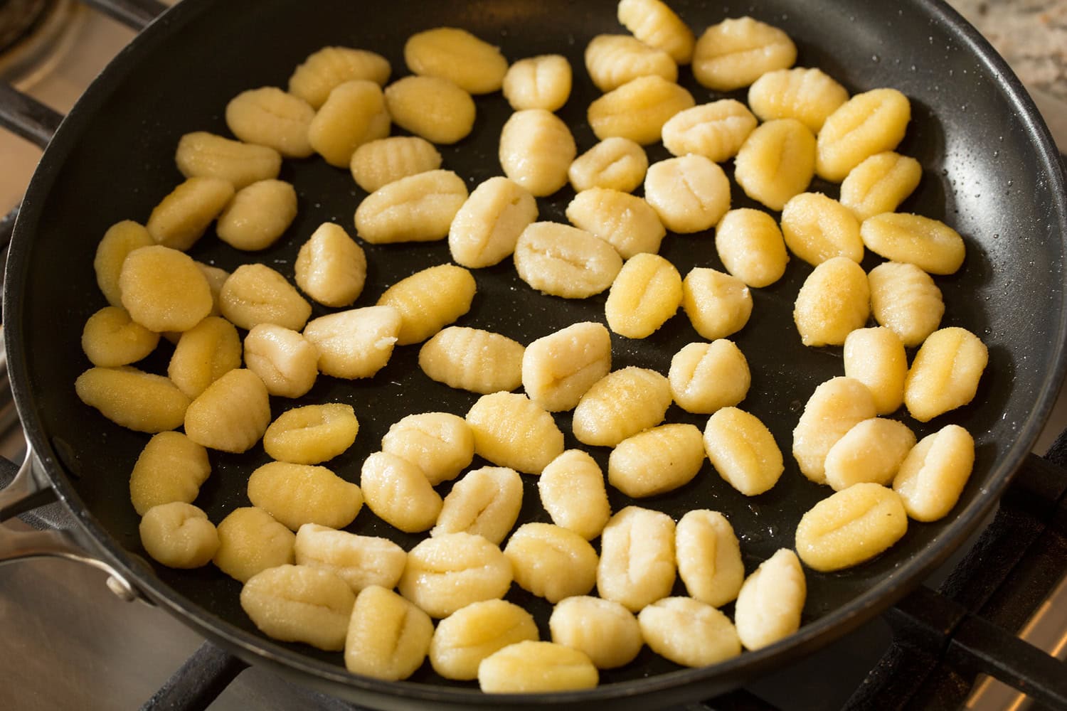 Gnocchi being sauteed in a skillet.