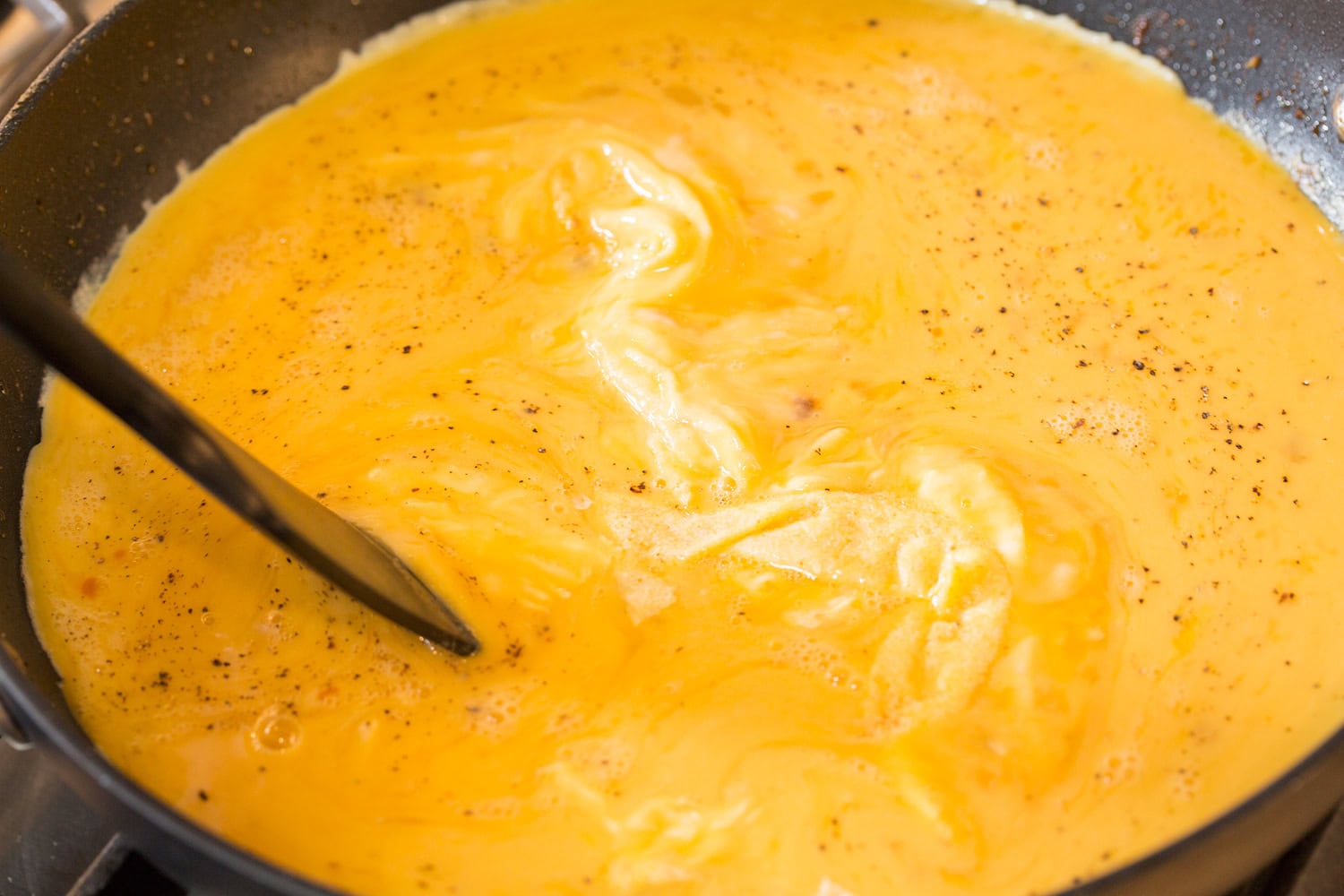 Stirring scrambled eggs in a non-stick skillet with a spatula.